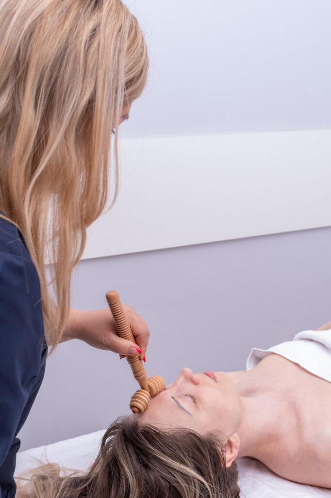 Professional Maderotherapy for skin tightening using natural wood tools for a lifted appearance.